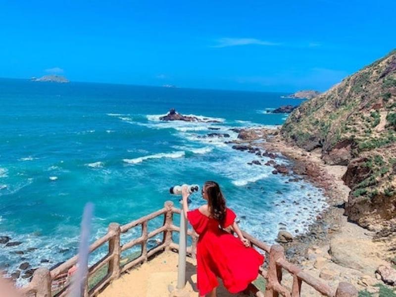 Hình ảnh một cặp đôi đang đi xe máy trên con đường ven biển Quy Nhơn với cảnh biển đẹp phía sau, thể hiện sự tự do khi đi lại bằng xe máy.