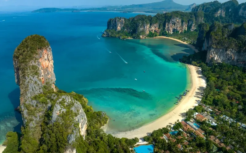 Hình ảnh biển Quy Nhơn trong xanh, cát trắng trải dài, một người đang thư giãn trên võng dưới bóng cây dừa, thể hiện sự yên bình, tự do của du lịch tự túc.
