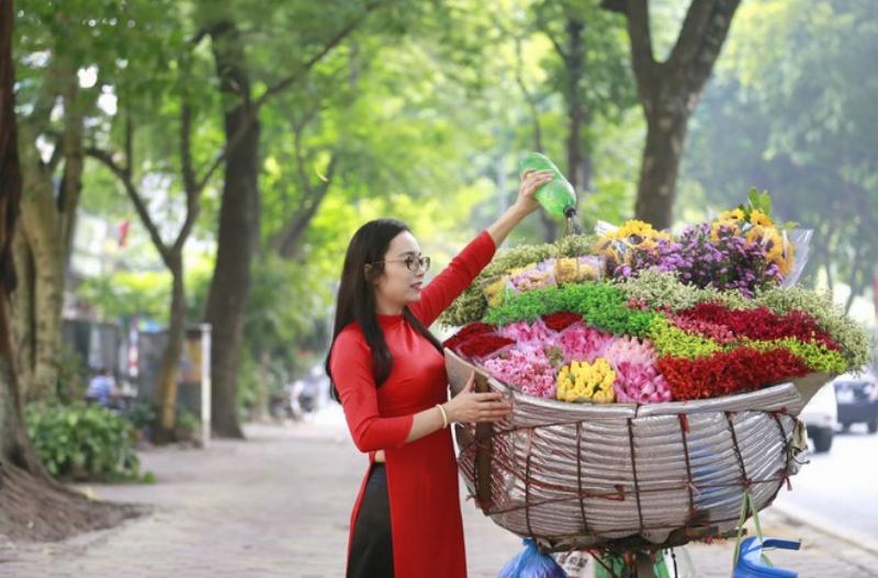 Hình ảnh thiếu nữ Hà Nội trong tiết trời mùa thu, với lá vàng rơi và xe đạp chở hoa