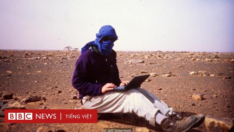 Hình ảnh một người làm kinh doanh ngồi làm việc trên laptop, phía sau là bản đồ thế giới hoặc hình ảnh kết nối mạng lưới toàn cầu