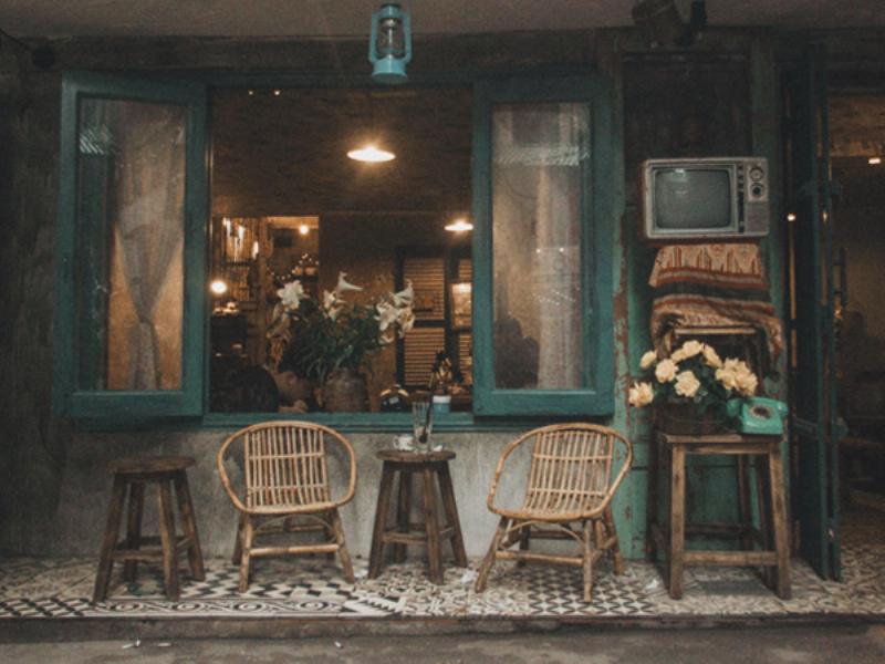 Hình ảnh nội thất của một quán cafe vintage ở Đà Nẵng, với đồ nội thất cũ, tường gạch thô, sàn gạch bông và ánh sáng vàng ấm áp, tạo không gian hoài cổ, lý tưởng để chụp ảnh "sống ảo".