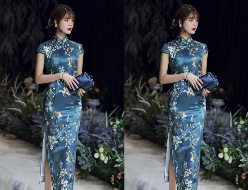 Một mẫu sườn xám cách tân hiện đại, với cổ tròn thấp, tay ngắn và chiều dài ngang gối, họa tiết hoa lá trẻ trung trên nền vải sáng màu.